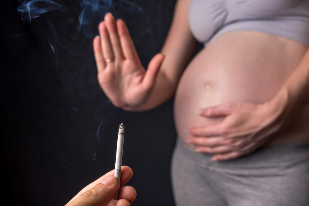 pregnant woman saying no thanks to a offered cigarette.