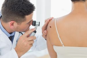 Doctor examining a mole on a patient's back
